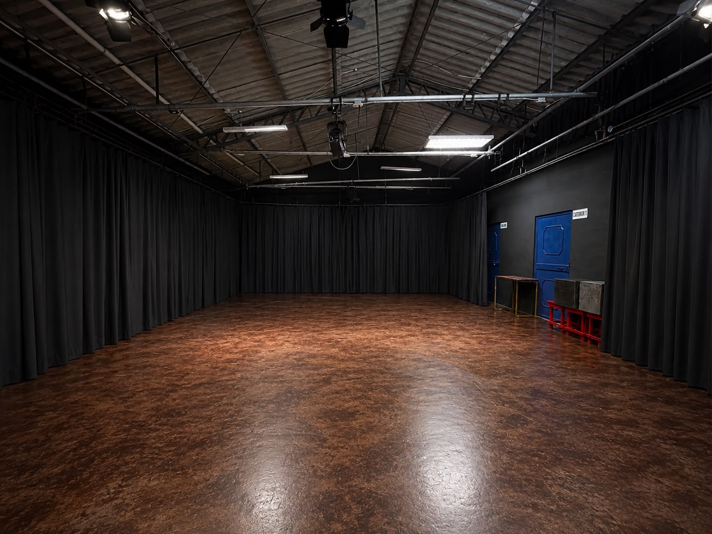 Estudio 6 del ITV: sala amplia multiuso con cortinas negras, piso de madera y parrilla de luces